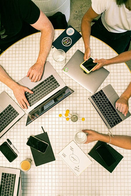 pexels photo 3194519 3194519 Top view of a team collaborating with laptops, phones, and notes in a modern office.